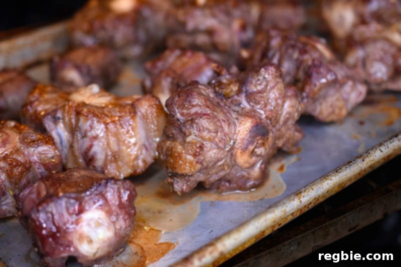 Broiled oxtails are shown on a rimmed baking sheet.
