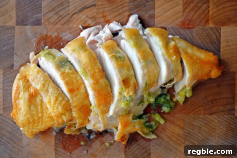 An overhead shot of elegantly sliced Ginger-Scallion Chicken on a wooden cutting board, ready to be served.