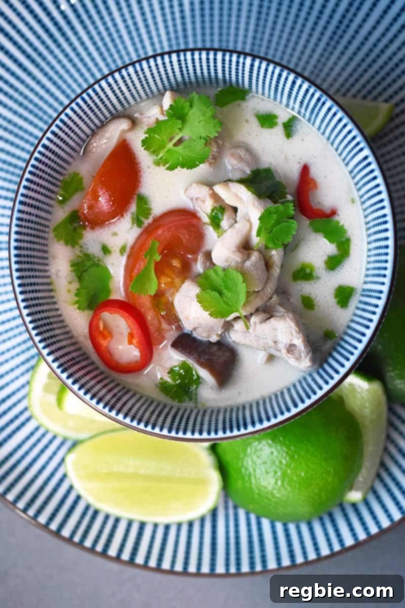 An overhead shot of a bowl of delicious Tom Kha Gai, a paleo and Whole30 Thai coconut chicken soup, garnished with fresh lime slices.