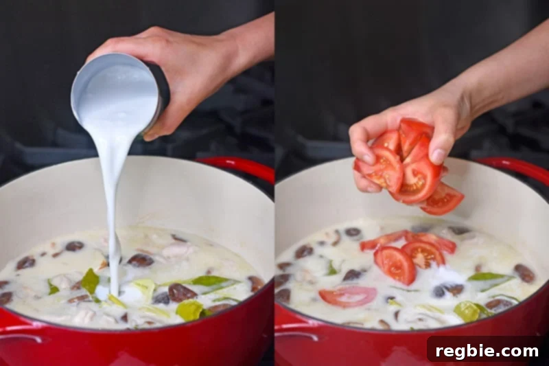 Adding the final can of coconut milk and fresh tomato slices to a pot of home cooked paleo Tom Kha Gai.