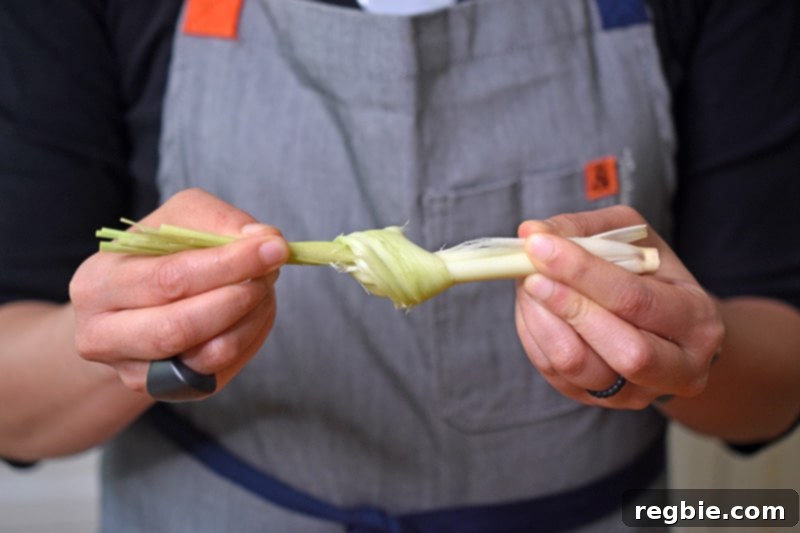 A properly smashed stalk of lemongrass, tied into a knot, ready to infuse a pot of healthy Tom Kha Gai.