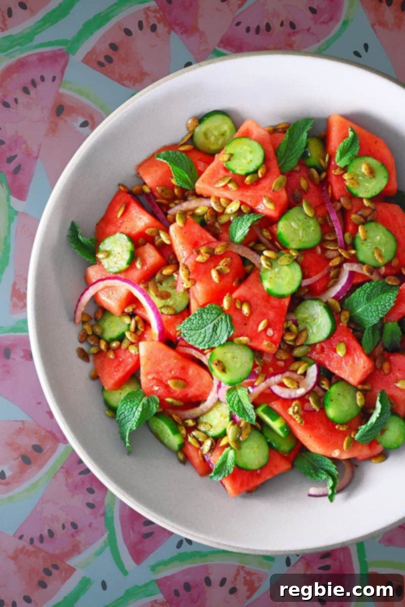 Fiesta Watermelon Cucumber Salad 2 Overhead shot of a vibrant bowl of Mexican watermelon and cucumber salad, garnished with fresh mint and smoky pepitas.