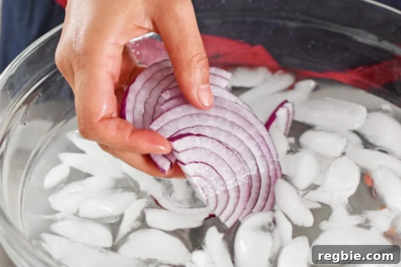 Fiesta Watermelon Cucumber Salad 6 Someone soaking thinly sliced red onions in a bowl of ice water, a technique to mellow their flavor.