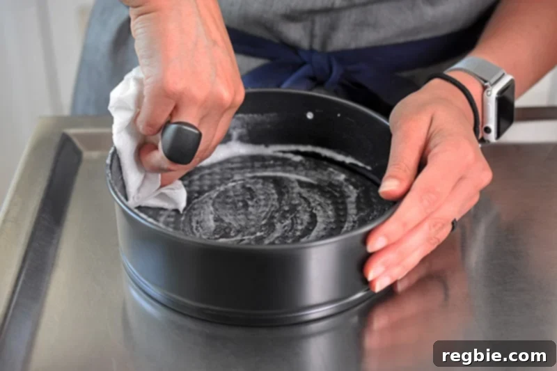 Greasing a 7-inch springform pan with coconut oil in preparation for making a vegan No-Bake Matcha Cheesecake.