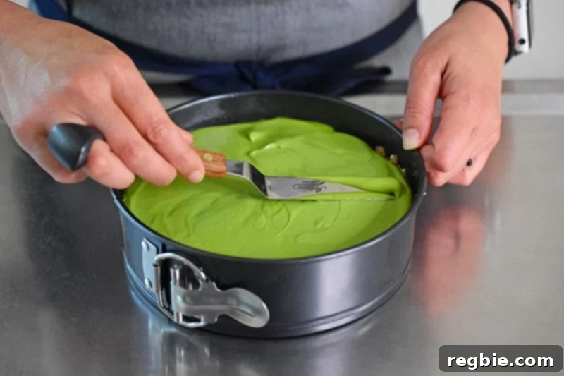 Smoothing the top of the vegan and paleo No-Bake Matcha Cheesecake filling with an offset spatula for a perfect finish.