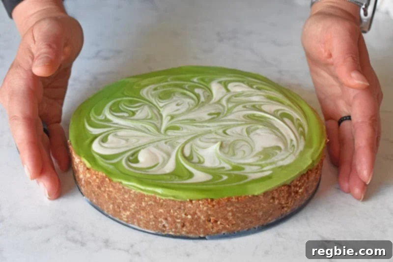 Two hands reaching for a perfectly sliced healthy paleo No-Bake Matcha Cheesecake, showcasing its creamy green filling.