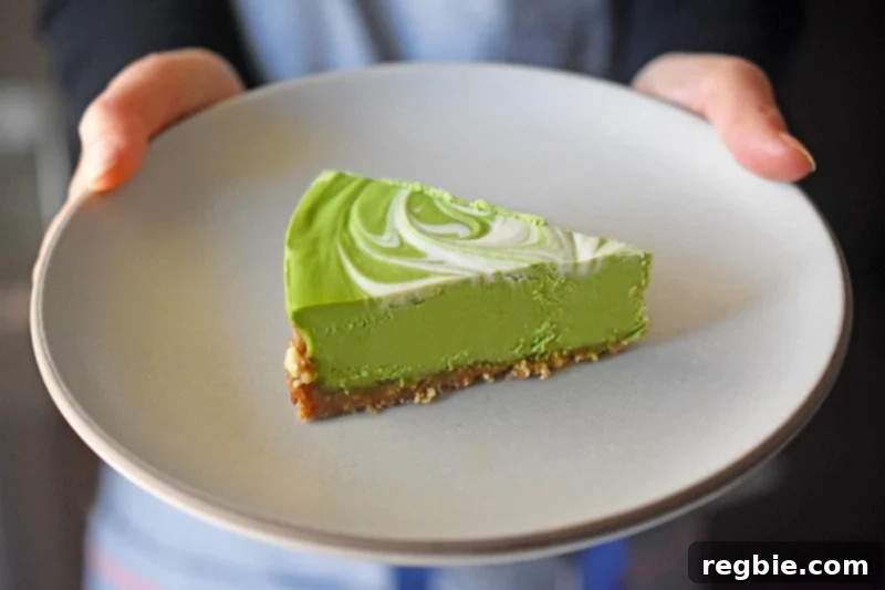 A perfectly portioned slice of No-Bake Matcha Cheesecake presented on a modern gray plate.