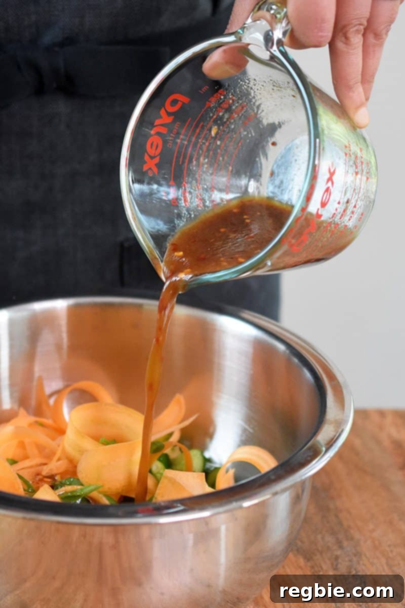 Pour the all-purpose stir-fry dressing into the bowl with the cucumbers, ribboned carrots, and sliced scallions.