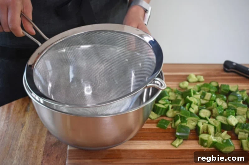 Placing a colander or fine meshed strainer inside a metal bowl, ready for the cucumbers.