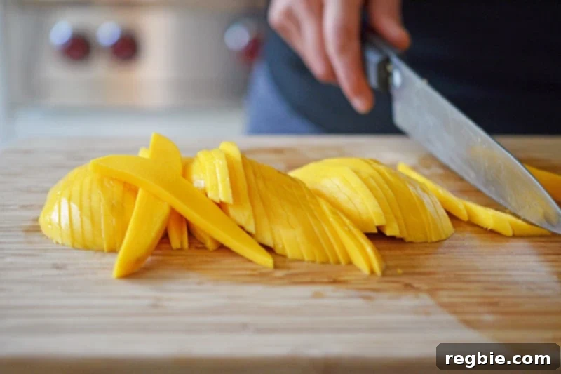 Zesty Mango Cabbage Crunch 5 Someone expertly slicing a ripe Ataulfo mango on a cutting board.