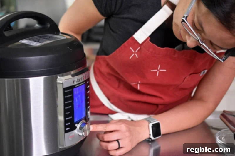 A woman leaning over to program her Instant Pot Ultra, setting it to cook under high pressure.