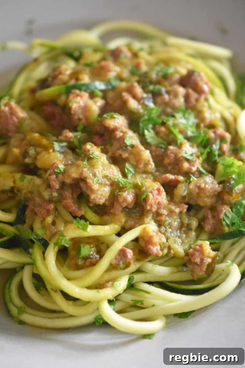 A tantalizing closeup shot of Instant Pot Zucchini Bolognese generously layered on top of tender zucchini noodles, garnished with fresh herbs.