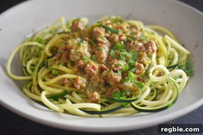 A beautiful side shot of creamy Instant Pot Zucchini Bolognese resting on a bed of fresh zucchini noodles in a shallow bowl, highlighting its perfect texture and rich color.