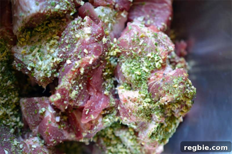 Raw pork shoulder cubes, visibly coated with Sunny Paris Seasoning and fish sauce, ready for slow cooking.