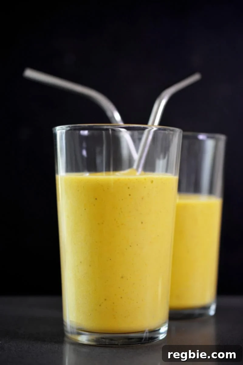 Sun-Kissed Wellness Smoothie 4 Two elegantly presented cups of golden glow smoothie, complete with reusable metal straws, highlighting its inviting color and texture.