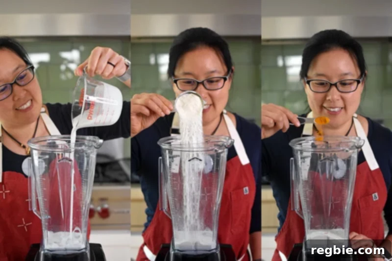 Sun-Kissed Wellness Smoothie 5 Michelle Tam expertly adding the initial ingredients – creamy coconut milk, beneficial collagen peptides, and vibrant turmeric powder – into a powerful Vitamix blender for the Golden Glow Smoothie, demonstrating the first step in preparation.