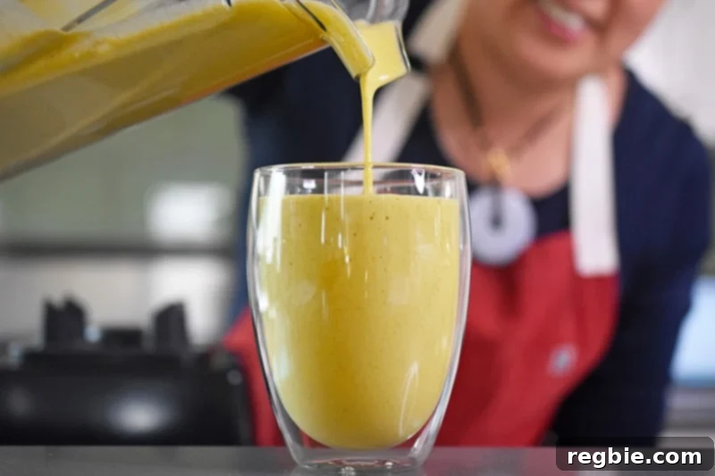 Sun-Kissed Wellness Smoothie 8 A smooth, golden glow smoothie being carefully poured from a high-speed blender into a serving cup, showcasing its inviting color and rich texture.