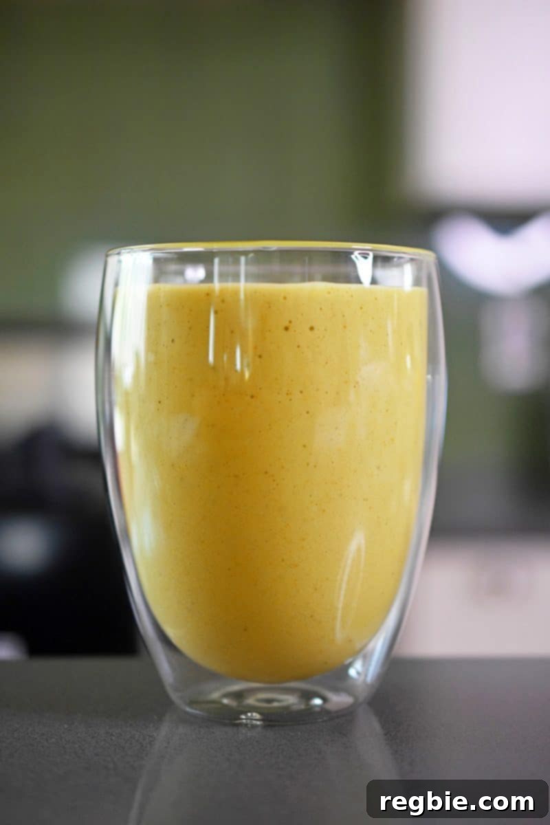 Sun-Kissed Wellness Smoothie 9 A tempting close-up of a single cup filled to the brim with the creamy, rich paleo golden glow smoothie, inviting you to take a sip.