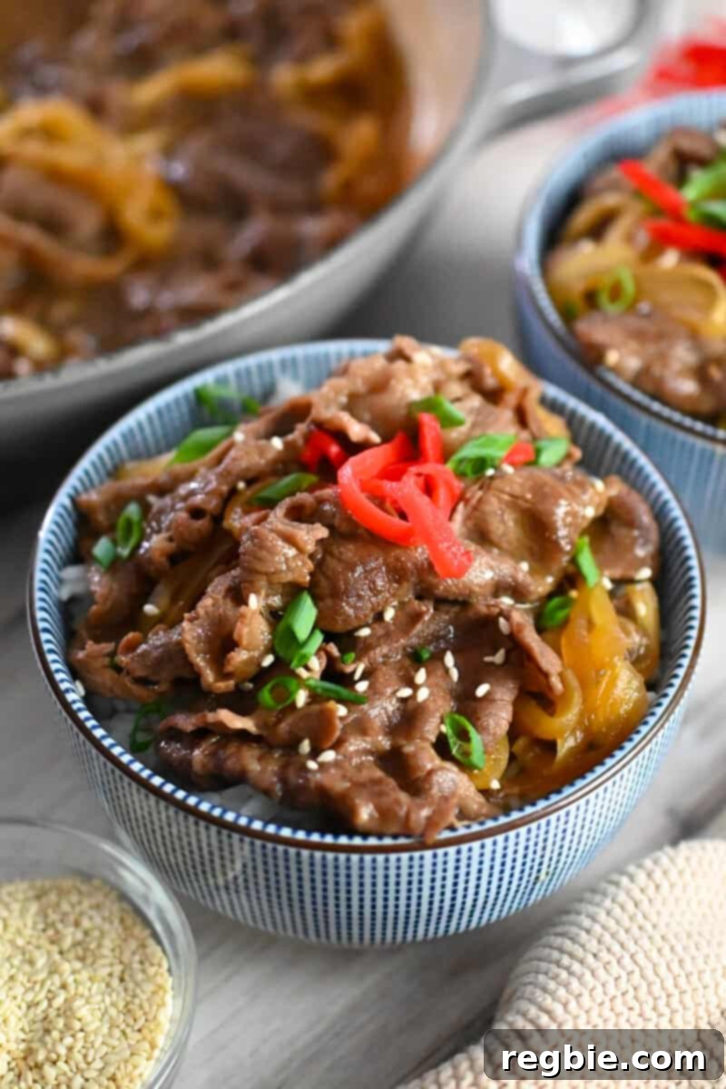 A vibrant close-up of a blue and white bowl filled with Gyudon, a Japanese beef and rice bowl, elegantly topped with bright red pickled ginger and fresh sliced green onions.