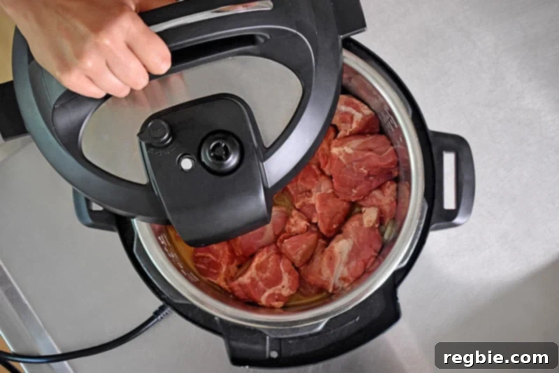 Closing and locking the lid on the Instant Pot containing the Magic Pork ingredients, preparing for pressure cooking.