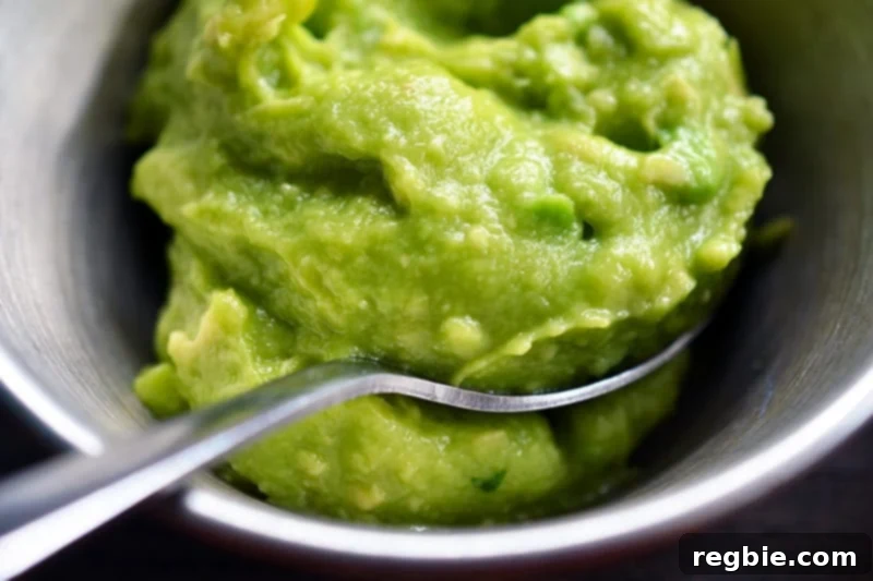 Avocado Dream Dip 2 Delicious 5-ingredient guacamole in a rustic bowl with a serving spoon, garnished with fresh cilantro, ready to be enjoyed.