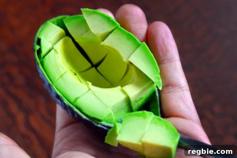 Avocado Dream Dip 7 Half an avocado is expertly diced into perfect ¾-inch cubes and held in a hand, showcasing its fresh green color before being added to the mixture.