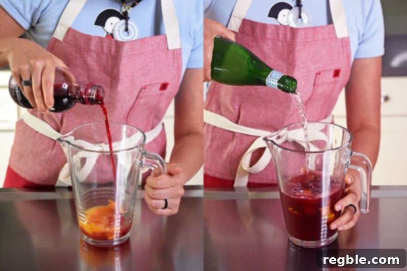 A person in a red apron is pouring pomegranate juice and sparkling water into a pitcher.