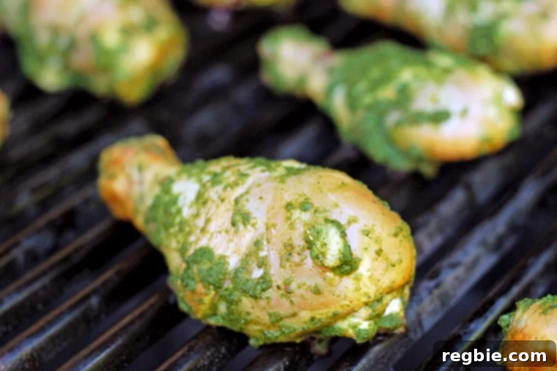 Marinated Fiona’s Phenomenal Grilled Green Chicken pieces being carefully placed onto a hot grill for cooking.