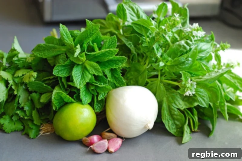 A selection of fresh herbs, onion, garlic, and limes arranged, ready to be blended for Fiona's Green Chicken marinade.
