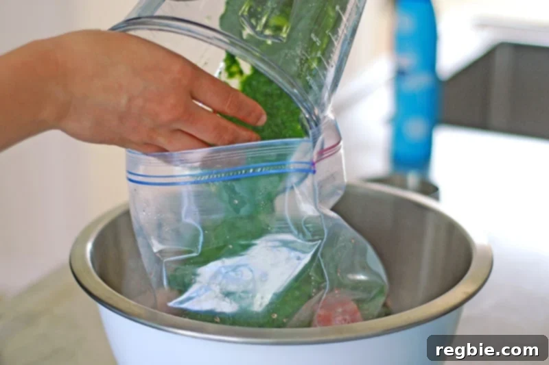 Pouring the vibrant green Whole30 marinade over raw chicken pieces inside a Ziplock bag.