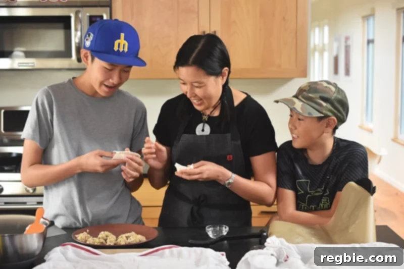 A mom and two kids are happily wrapping Paleo Pot Stickers in a brightly lit kitchen.