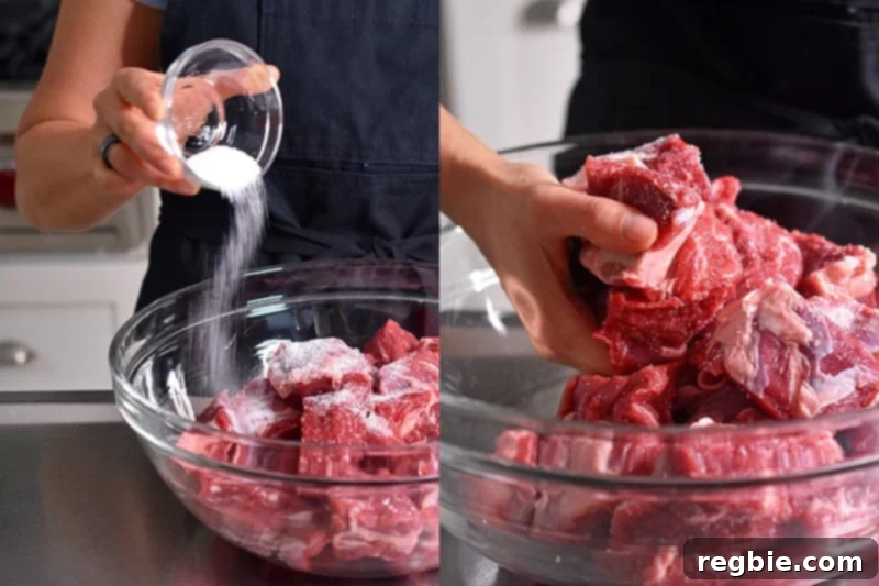 Cubes of beef chuck roast are seasoned and tossed with kosher salt, preparing them for cooking.
