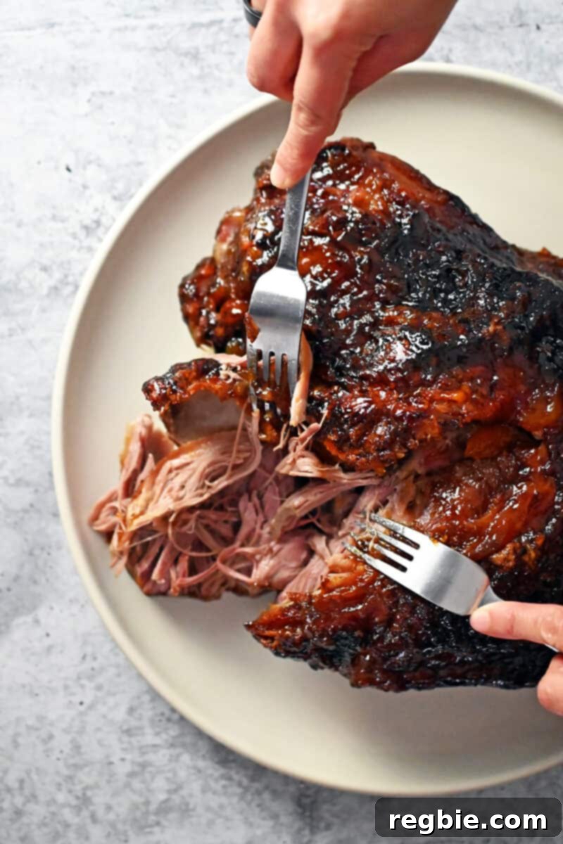 Effortless Peach Glazed Pork Roast 2 Two forks are shredding a slow roasted pork shoulder roast before being served.