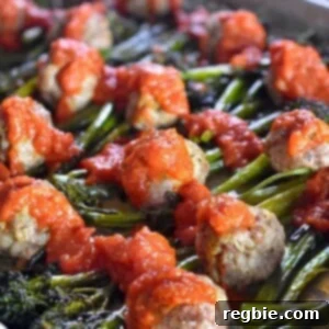Diagonal shot of Sheet Pan Meatballs and Broccolini supper topped with marinara sauce.
