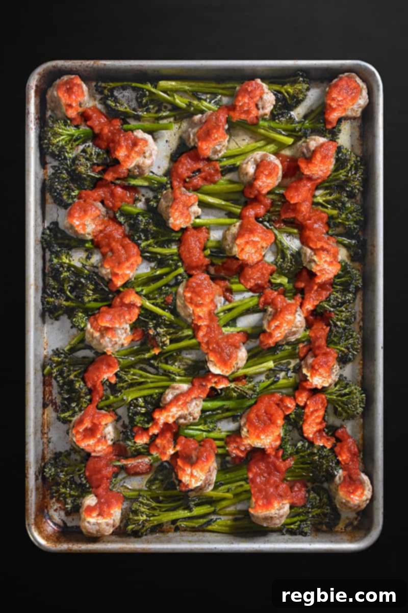 Overhead image of Sheet Pan Meatballs and Broccolini with vibrant red marinara sauce drizzled over it.