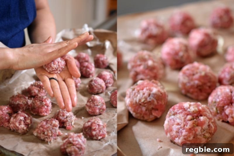 Two hands are actively rolling bulk sausage into uniform meatballs on a cutting board or clean surface.