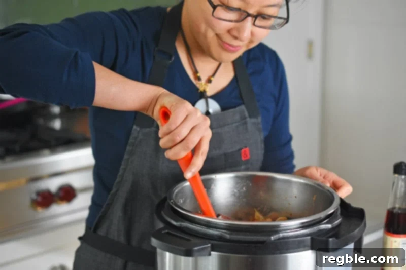 A smiling woman stirring Instant Pot Beef Stew in an open Instant Pot.