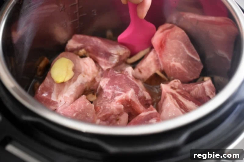 A closeup of the inside of an Instant Pot, showing a hand stirring the contents with a silicone spatula, scraping the bottom.