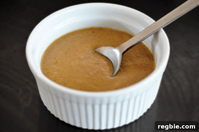 A ramekin overflowing with thick, savory Whole30 chicken gravy, promising rich flavor.