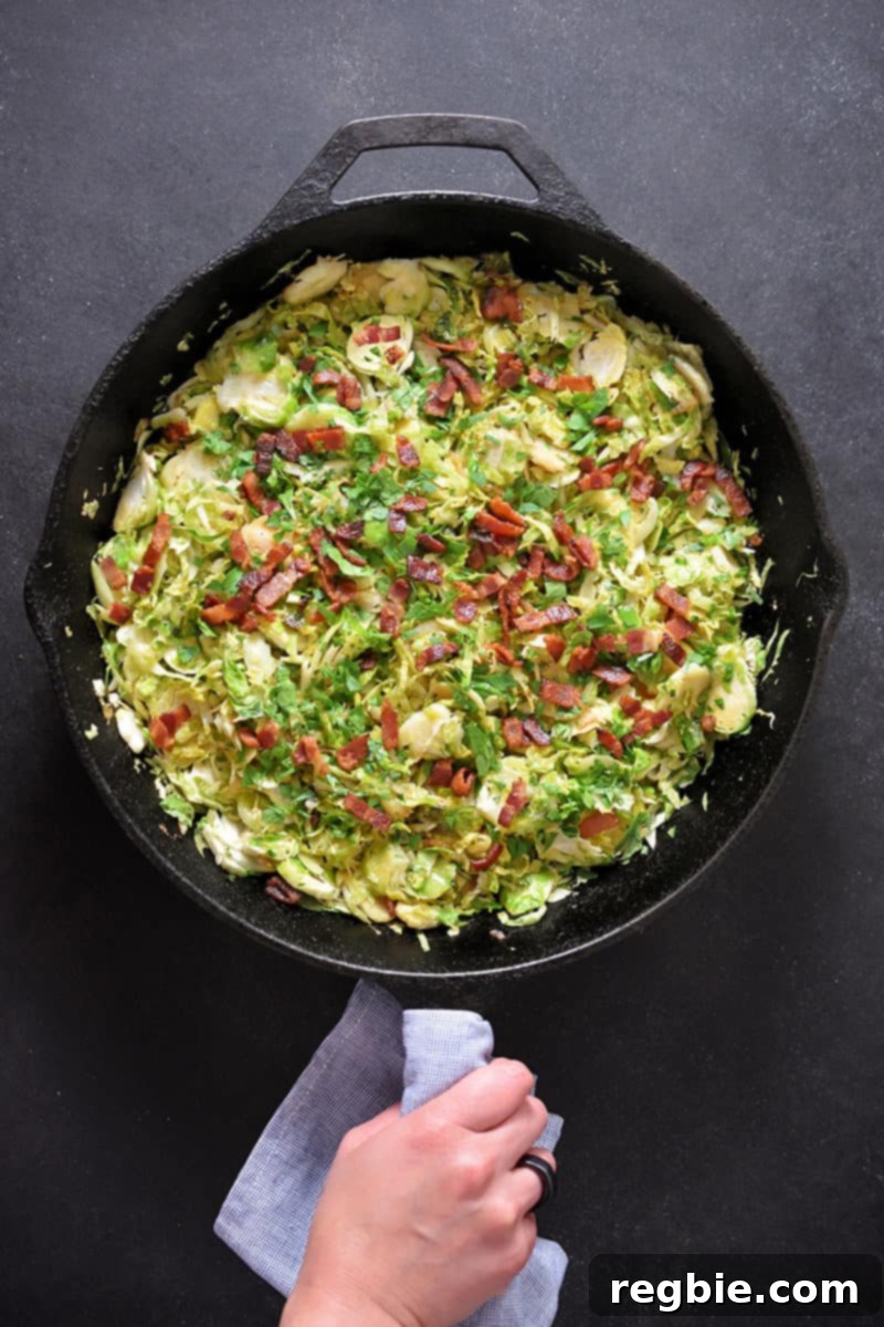 Crispy Bacon Brussels Sprouts 2 An overhead shot of a cast iron skillet filled with shaved brussels sprouts with bacon, ready to serve.