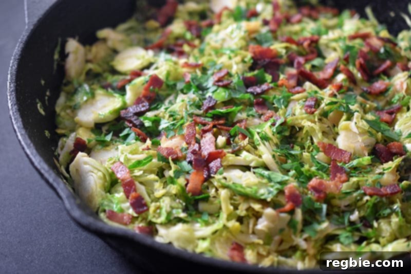 Crispy Bacon Brussels Sprouts 14 A close-up, side view of the finished Shaved Brussels Sprouts with Bacon in a cast iron skillet, showcasing its appealing texture and rich colors.