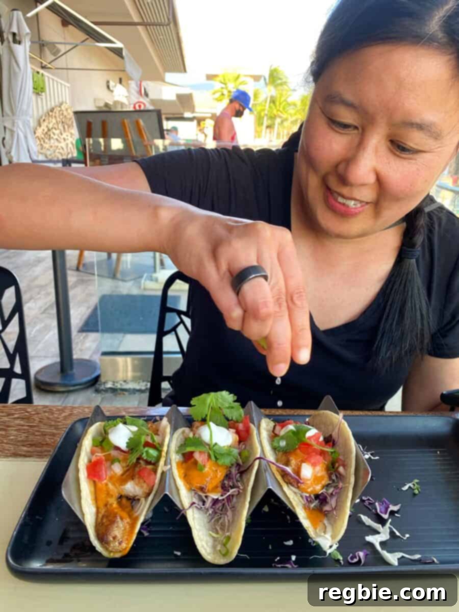 An Asian woman is squeezing lime juice on gluten-free fish tacos at Monkeypod in Maui