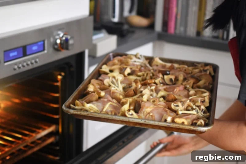 Placing the prepared sheet pan dinner into a hot oven to begin roasting.