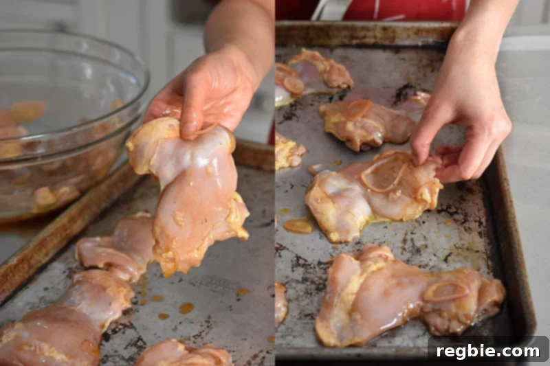 Placing marinated chicken thighs in a single layer on a rimmed baking sheet, ready for roasting.