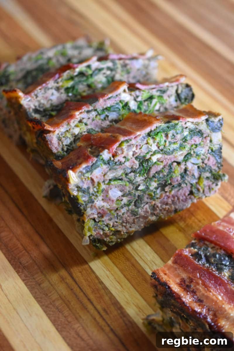 Easy Whole30 Paleo Keto Meatloaf Nut and Dairy Free 2 Closeup of Easy Paleo and Keto Meatloaf, perfectly sliced and ready to serve on a rustic wooden cutting board, showcasing its tender interior and crispy bacon topping.