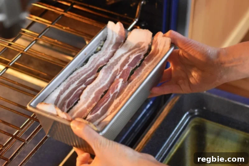 Easy Whole30 Paleo Keto Meatloaf Nut and Dairy Free 11 Carefully placing the bacon-topped meatloaf into the preheated oven for baking.