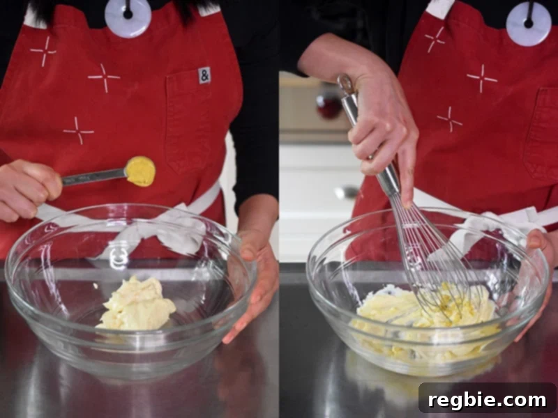 A spoonful of Dijon mustard being added to a bowl of mayonnaise, followed by vigorous mixing with a whisk to create a smooth, creamy dressing.