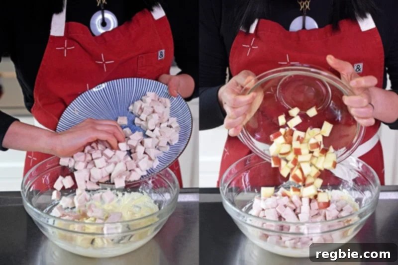 Cubed cooked chicken and the prepped apples are added into the large bowl with the mayonnaise dressing, ready for mixing.