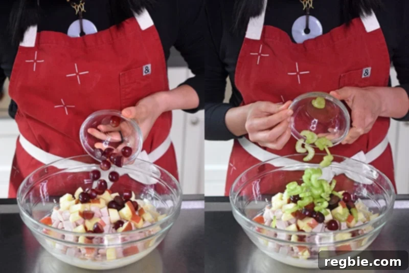 Red grapes and thinly sliced celery are added to the bowl, joining the chicken and apples to complete the main Waldorf salad components.