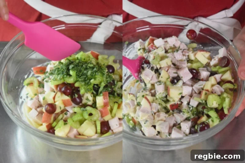Fresh minced herbs, specifically tarragon, are gently folded into the chicken Waldorf salad mixture in a large bowl.